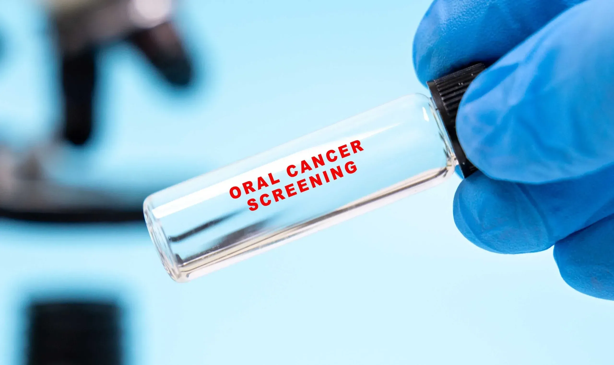 Gloved hand holding a vial labeled oral cancer screening