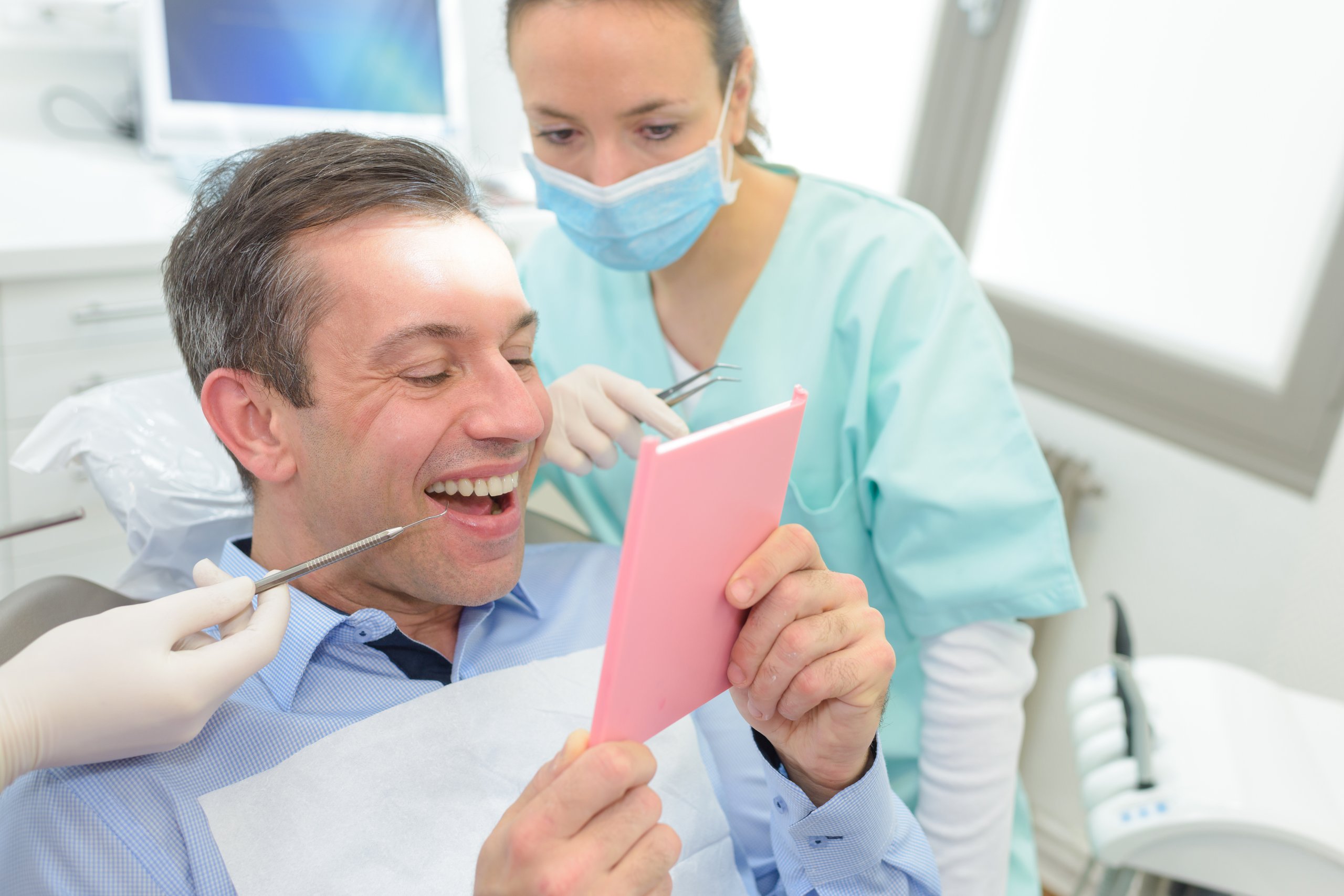 Patient looking at mirror after tooth extraction, illustrating restorative dental treatment